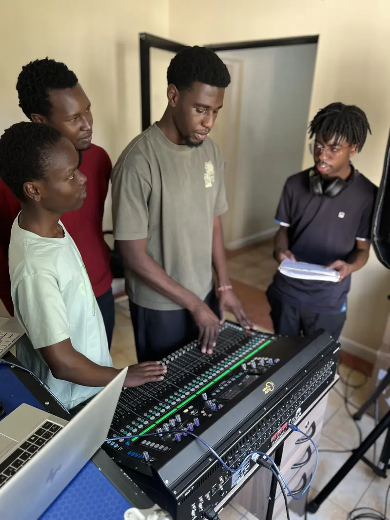 Mbaji Training Academy learners working together on a digital mixing console